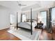 Bright bedroom boasts a tray ceiling, four-poster bed, wood floors, and a stylish accent rug at 350 Fountain Oaks Ln, Atlanta, GA 30342