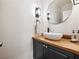 Chic powder room featuring a stylish sink, wood countertop, modern fixtures, and a round mirror at 350 Fountain Oaks Ln, Atlanta, GA 30342
