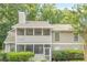 View of a two-story home with neutral siding, a screened in porch, landscaping, and a roof chimney at 1102 Wynnes Ridge Se Cir, Marietta, GA 30067