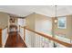 Second floor hallway with hardwood floors, decorative light fixture and wood railing at 3595 Millwater Xing, Dacula, GA 30019