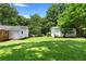 Expansive backyard with lush green grass and mature trees, featuring a storage shed at 501 Samaritan Dr, Cumming, GA 30040
