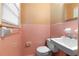 Cozy pink bathroom with matching tiled walls, featuring a toilet, sink, and accessories at 501 Samaritan Dr, Cumming, GA 30040