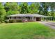 Charming brick home with a well-maintained lawn, mature trees, and a covered carport at 501 Samaritan Dr, Cumming, GA 30040