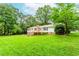 Spacious backyard featuring lush green grass, mature trees, deck with stairs, and chimney at 3156 Laurel Way, Snellville, GA 30078