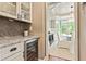 Butler's pantry with marble countertops, wine cooler, and glass cabinet with display shelves near dining room at 121 Fairway Overlook, Woodstock, GA 30188