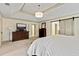Spacious main bedroom with a tray ceiling, dresser with TV, and a barn door leading to the en suite bathroom at 121 Fairway Overlook, Woodstock, GA 30188
