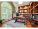 Bright office space featuring custom wood built-ins, a large window with shutters and hard wood flooring at 121 Fairway Overlook, Woodstock, GA 30188