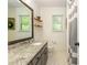 Bright bathroom with granite countertops, two windows, and a shower with a gray striped shower curtain at 210 Hunters Vw, Roswell, GA 30075