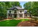 Stately stucco home featuring a well-manicured lawn and complemented by lush surrounding trees at 210 Hunters Vw, Roswell, GA 30075