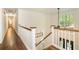 Bright hallway with hardwood floors, white railing, and large arched window overlooking lush greenery at 210 Hunters Vw, Roswell, GA 30075