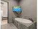 Modern bathroom featuring a standalone tub with marble surround, grey walls, and access to other rooms at 6394 Wood Valley Rd, Douglasville, GA 30134