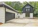 Charming two-story home with white brick and black trim, complemented by a spacious driveway and lush greenery at 6394 Wood Valley Rd, Douglasville, GA 30134