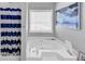 Bathroom with a tub, a shower with a blue and white curtain, and natural light at 250 Daileys Plantation Dr, Mcdonough, GA 30253