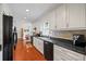 Well-lit kitchen with stainless steel sink, hardwood floors, white cabinetry, modern appliances, and brick backsplash at 705 Clubhouse Se Dr, Conyers, GA 30094