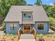 Charming two-story blue home with a wooden entryway and manicured landscaping in a wooded setting at 6900 Driskell Cir, Cumming, GA 30041