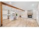 Open-concept living space with a modern kitchen, dining area, stone fireplace, and wood beam accents at 6900 Driskell Cir, Cumming, GA 30041
