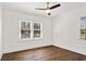 Bright bedroom featuring hardwood floors, white trim, a ceiling fan, and natural light from two windows at 4178 Castle Pines Ct, Tucker, GA 30084