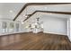 Open floor plan with hardwood floors, white walls, wood beams, view to the kitchen, and access to an outdoor deck at 4178 Castle Pines Ct, Tucker, GA 30084