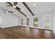 Living room with hardwood floors, many windows, wood beams, white walls, ceiling fans, and modern front door at 4178 Castle Pines Ct, Tucker, GA 30084