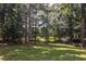 Lush backyard with mature trees, green grass, and a hint of the lake in the distance at 1587 Red Fox Sw Run, Lilburn, GA 30047