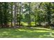 Serene backyard with lush grass, mature trees, and a glimpse of the nearby lake at 1587 Red Fox Sw Run, Lilburn, GA 30047