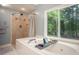 Bathroom features a soaking tub and separate shower with a picturesque backyard view at 1587 Red Fox Sw Run, Lilburn, GA 30047