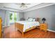 Inviting bedroom featuring hardwood floors, tray ceiling, and a large window at 1587 Red Fox Sw Run, Lilburn, GA 30047
