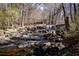 A scenic creek flowing through a rocky landscape with a small waterfall and surrounding woods at 1587 Red Fox Sw Run, Lilburn, GA 30047