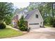 View of attached two-car garage with an automatic door plus manicured lawn and beautiful plantings at 1587 Red Fox Sw Run, Lilburn, GA 30047