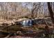 A picturesque waterfall cascading over rocks in a wooded area, surrounded by trees and foliage at 1587 Red Fox Sw Run, Lilburn, GA 30047