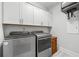 Well-lit laundry area featuring gray appliances and storage cabinets above the washer and dryer at 18 Peachtree Ne Ave # 5, Atlanta, GA 30305