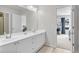 Bathroom featuring a double vanity, large mirror, and a view of the bedroom, which has a large window at 2845 Aquitania Ln, Cumming, GA 30040