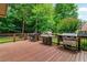 Spacious wooden deck area featuring multiple grills and a wooded backdrop, perfect for outdoor entertaining at 2845 Aquitania Ln, Cumming, GA 30040