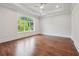 Large bedroom with hardwood floors, a ceiling fan, and a large window with a treed view at 10745 Shallowford Rd, Roswell, GA 30075