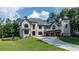 Stunning white brick home on a manicured lawn, showcasing architectural details and a three-car garage at 10745 Shallowford Rd, Roswell, GA 30075