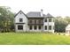 Back exterior view of a white brick home with a dark trim balcony, featuring a well-manicured lawn at 10745 Shallowford Rd, Roswell, GA 30075