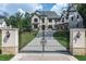 Grand gated entrance with white brick columns and a sweeping drive leading to a luxurious white brick home at 10745 Shallowford Rd, Roswell, GA 30075