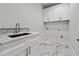 Well-lit laundry room with marble countertops, white cabinets, and a modern sink and faucet at 10745 Shallowford Rd, Roswell, GA 30075