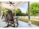 Covered back patio includes rocking chairs with views of the expansive fenced yard and landscaping at 3012 Keeneland Blvd, Mcdonough, GA 30252