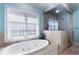 Bright bathroom with a soaking tub under a window and a glass-enclosed shower featuring neutral stone tile at 785 Wilson Nw Rd, Atlanta, GA 30318