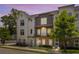 Townhome with brick facade, gray siding, balcony, and manicured lawn, bathed in the warm hues of the evening sky at 3484 Orchard St, Atlanta, GA 30354