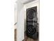 Modern laundry area features a sleek, stacked washer and dryer with an open white door and wood plank flooring at 3484 Orchard St, Atlanta, GA 30354