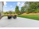View of a backyard patio with seating and a basketball hoop, surrounded by lush green grass and mature trees at 3962 Roberts Crest Dr, Suwanee, GA 30024