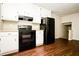 Functional kitchen featuring white cabinetry, modern black appliances, and hardwood floors at 6194 Golden Meadow Court Ct, Riverdale, GA 30296