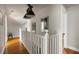 Upstairs hallway with hardwood floors, white railing, and stylish lighting at 1656 N Pelham Ne Rd, Atlanta, GA 30324