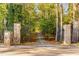 Stone gate opening onto a long driveway, winding through a lush, tree-lined landscape at 8316 Hewlett Rd, Sandy Springs, GA 30350