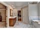 Bright bathroom with marble floors, soaking tub, dark wood vanity, and a view into the walk-in closet at 10195 Brier Mill Ct, Alpharetta, GA 30022