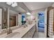 Bright bathroom with dual sinks, white countertop, decorative mirrors and lights, and a walk-in shower at 10195 Brier Mill Ct, Alpharetta, GA 30022