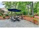 Beautiful outdoor patio with stone flooring, brick planters, dining set, and lush greenery at 10195 Brier Mill Ct, Alpharetta, GA 30022