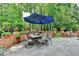 Outdoor patio with stone pavers, a dining set under an umbrella, and landscaped garden views at 10195 Brier Mill Ct, Alpharetta, GA 30022